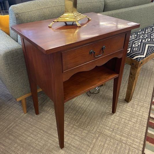 Wooden side table with a drawer in a room setting