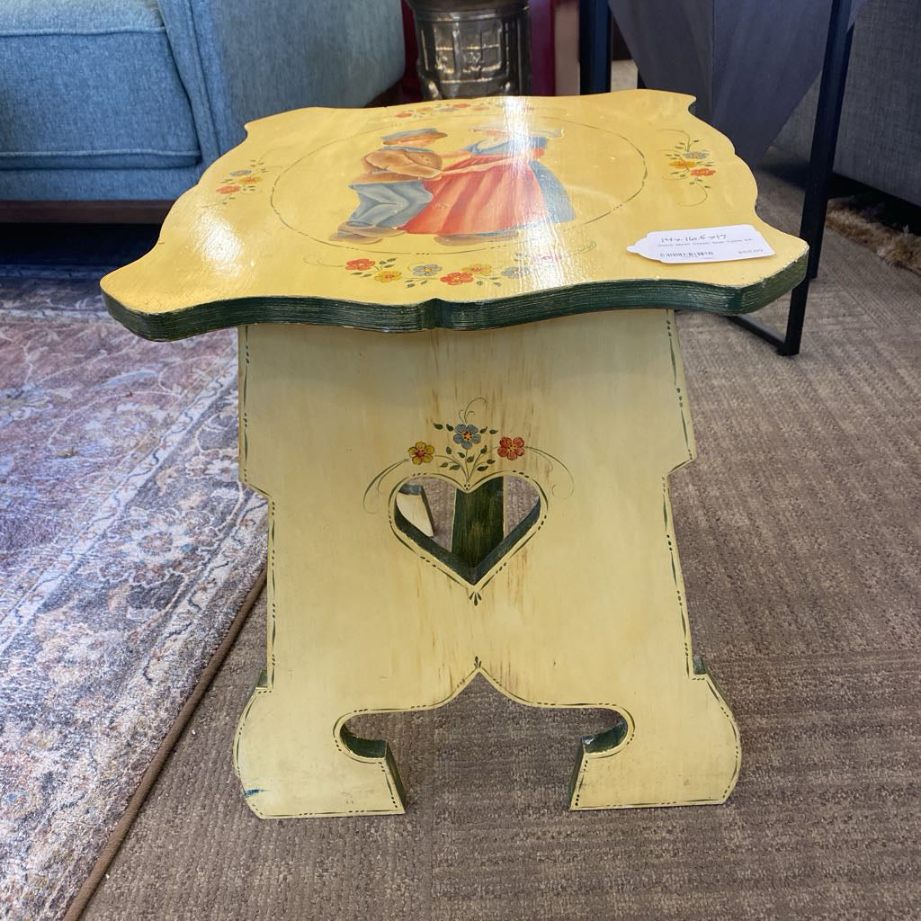 Decorative wooden table with artistic designs on a carpeted floor.