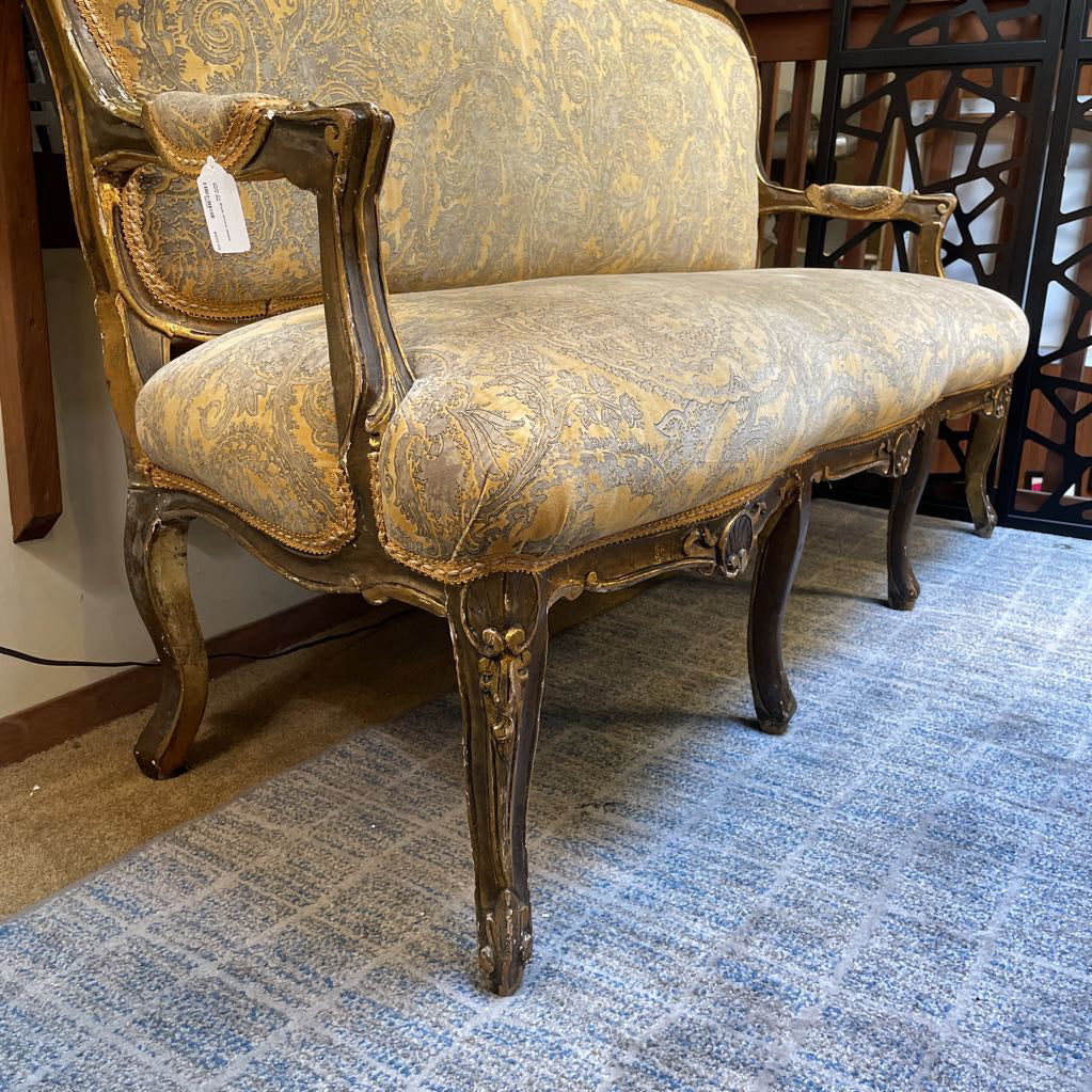 Vintage armchair with ornate design on a blue carpeted floor.