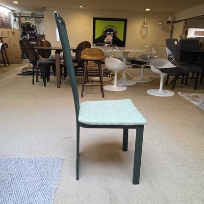 Chair with a green backrest and cushioned seat in a room with tables and chairs.