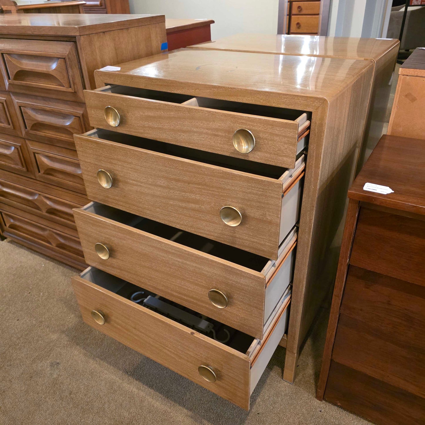 Wooden cabinet with multiple drawers and metallic handles in a room setting.
