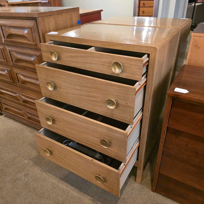 Wooden cabinet with multiple drawers and metallic handles in a room setting.