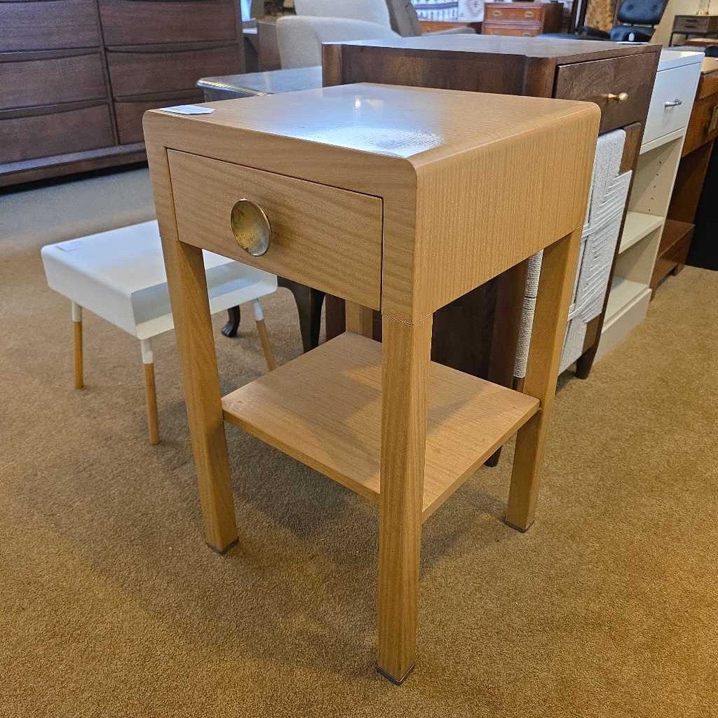 Wooden side table with a drawer and shelf in a furniture store setting