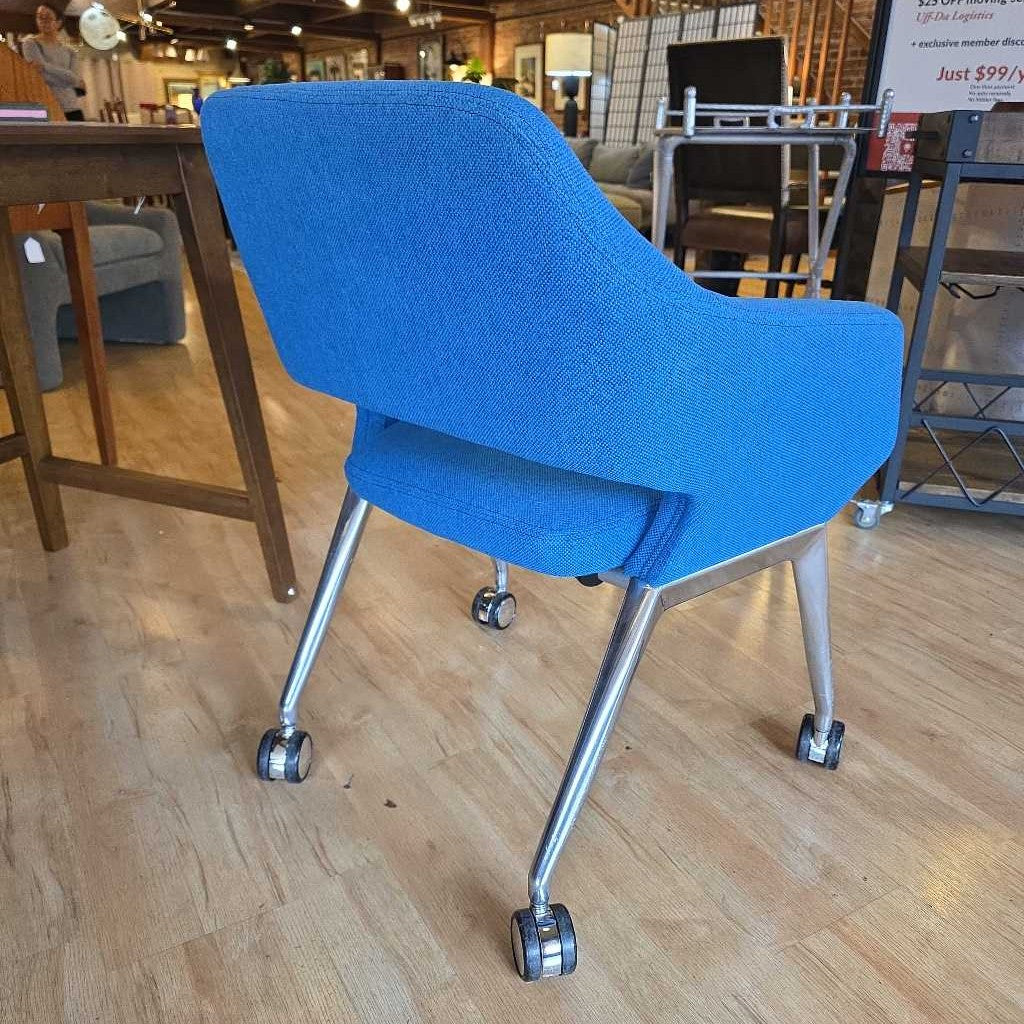 Blue office chair with wheels on a wooden floor in a store setting