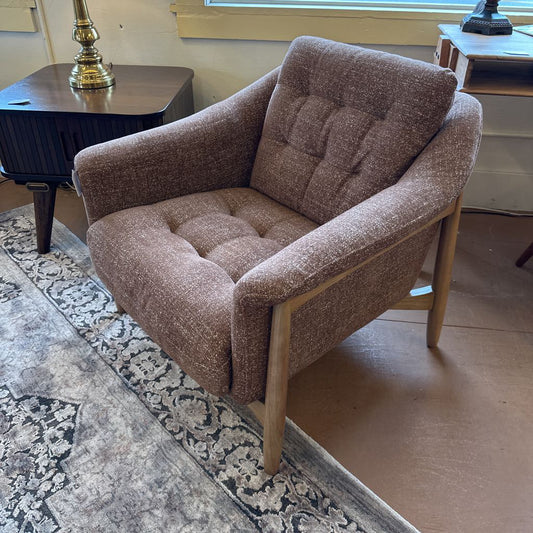 Brown upholstered armchair in a room with a patterned rug and wooden furniture.