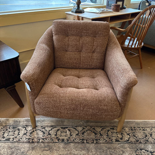 Brown armchair in a room with a desk and window