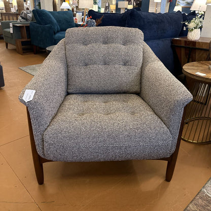 Gray armchair with wooden legs in a furniture store setting