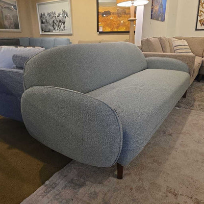 Gray sofa in a living room setting with other furniture and decor.