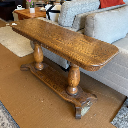 Wooden console table in a living room setting with a sofa and coffee table.