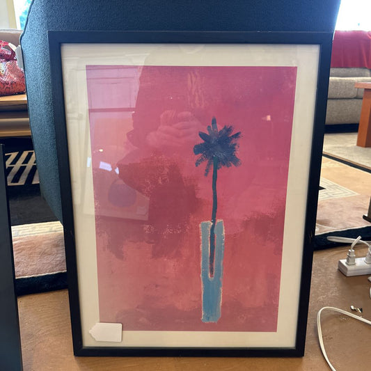 Framed artwork with a palm tree design on a red background