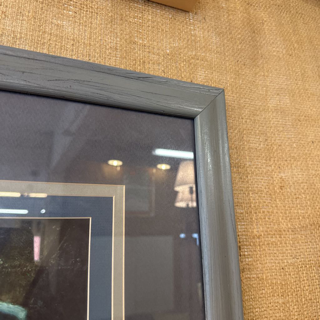 Framed artwork of a figure playing a guitar on a textured wall.