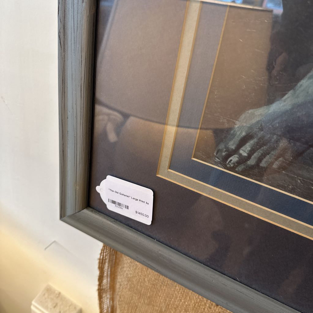 Framed artwork with a label on a white wall