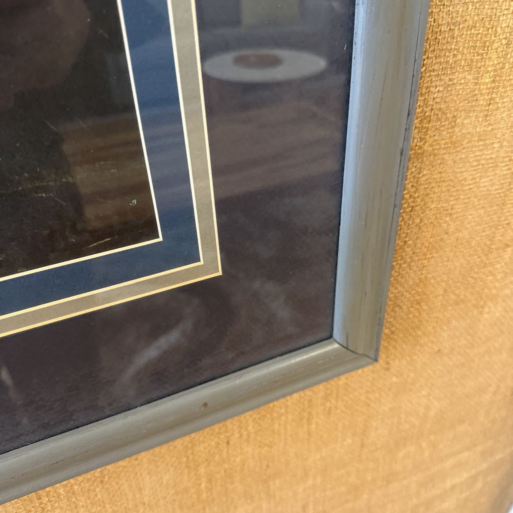 Close-up of a framed picture with a wooden frame on a textured surface.