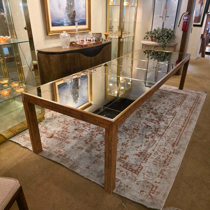 Glass display case with wooden frame in a room with a patterned rug and framed pictures.