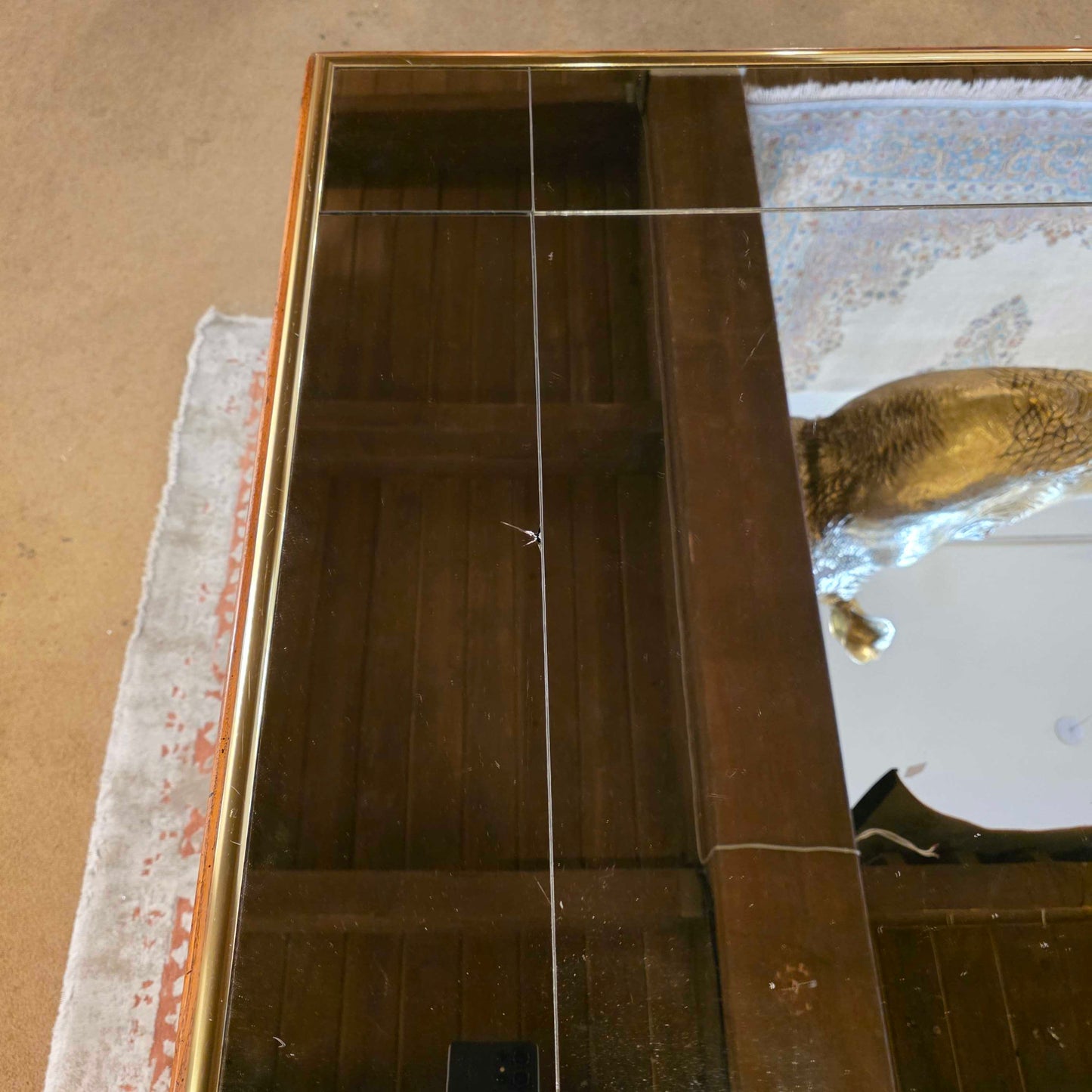 Large mirror with a gold frame on a textured wall.