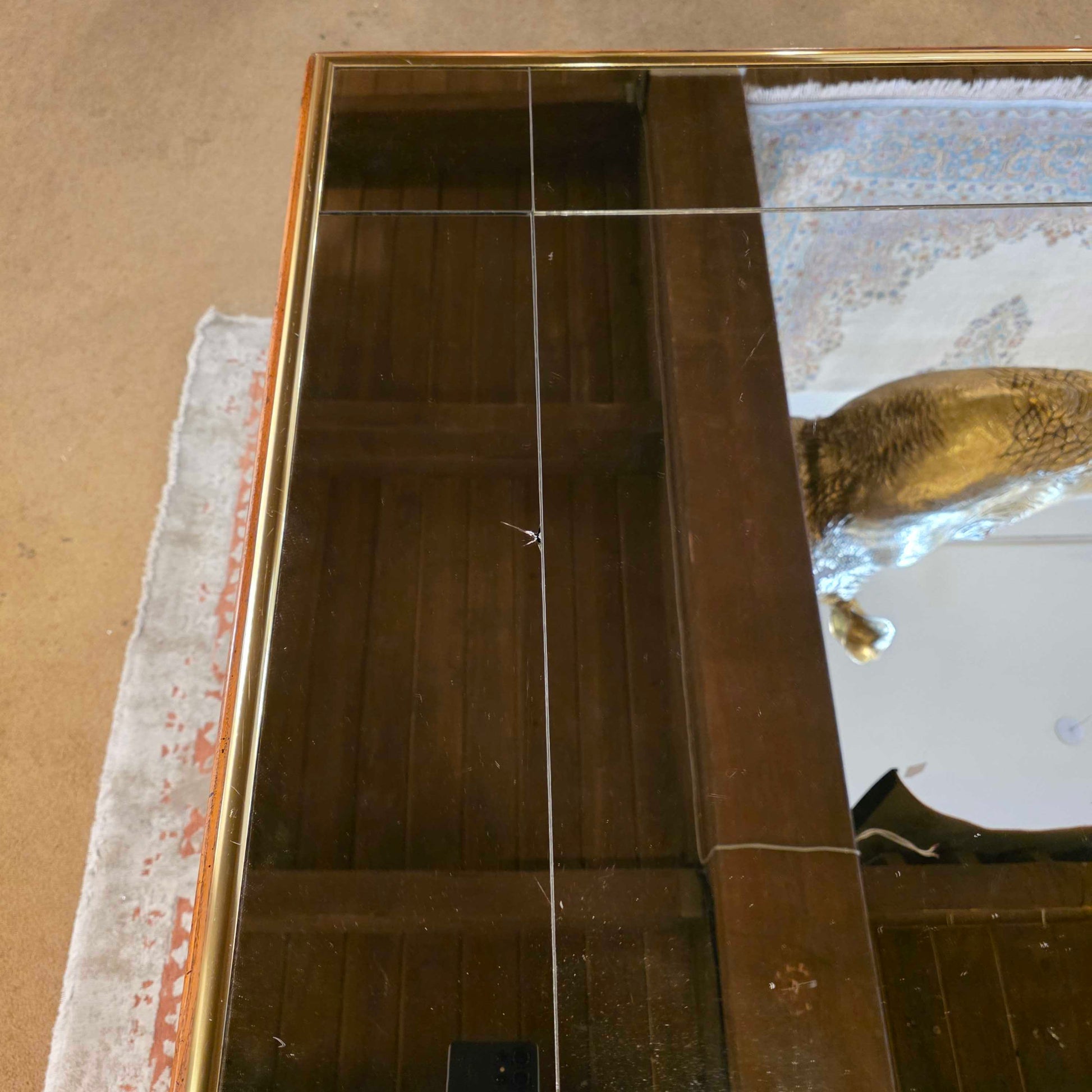 Large mirror with a gold frame on a textured wall.