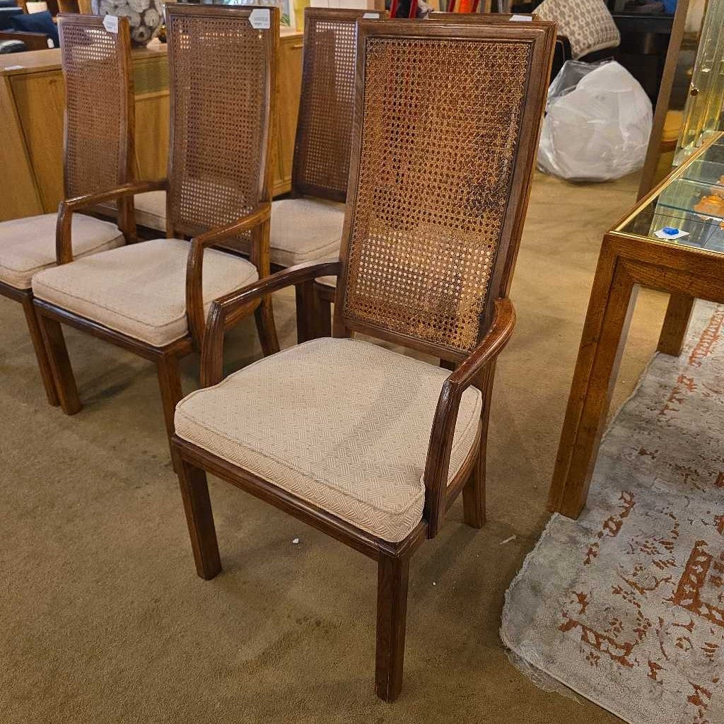 Set of four wicker chairs with beige cushions in a room setting.