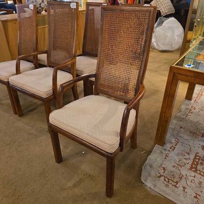 Set of four wicker chairs with beige cushions in a room setting.