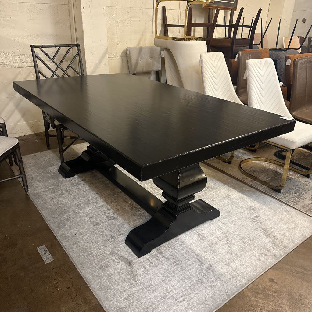 Black dining table in a showroom setting with chairs and other furniture.