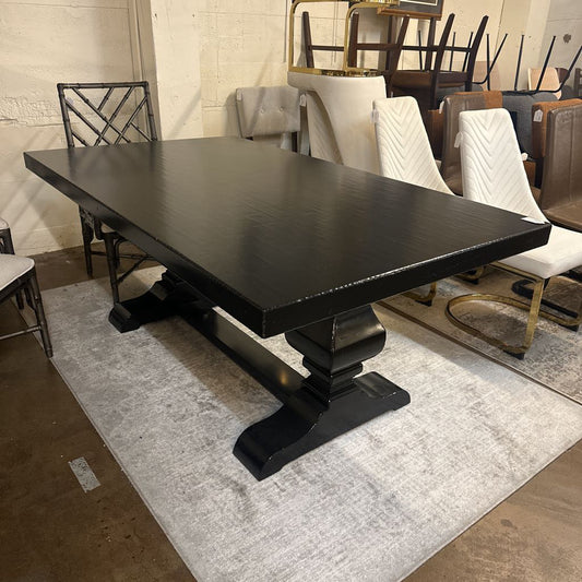 Black dining table in a showroom setting with chairs and other furniture.