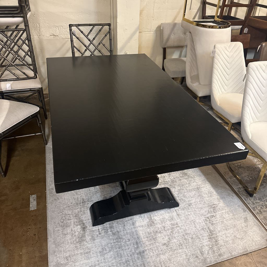 Black dining table in a showroom setting with chairs and decor.