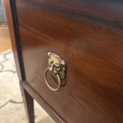 Wooden drawer with a brass lion head handle on a carpeted floor.
