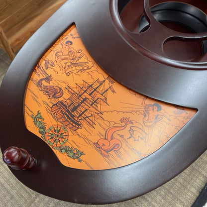 Decorative wooden reel with ship design on an orange background