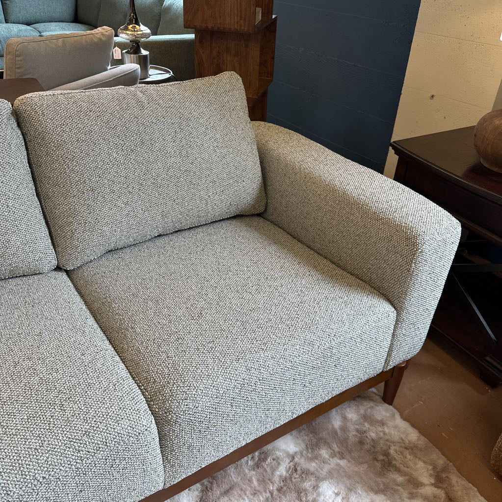 Gray textured sofa in a living room setting with a rug and furniture.