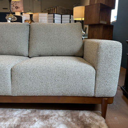 Gray textured sofa with wooden legs in a room setting