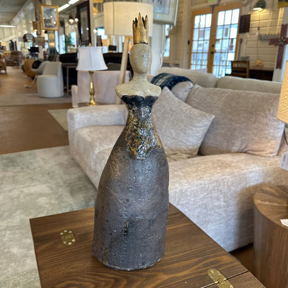 Decorative bottle sculpture on a wooden table with a living room setting in the background