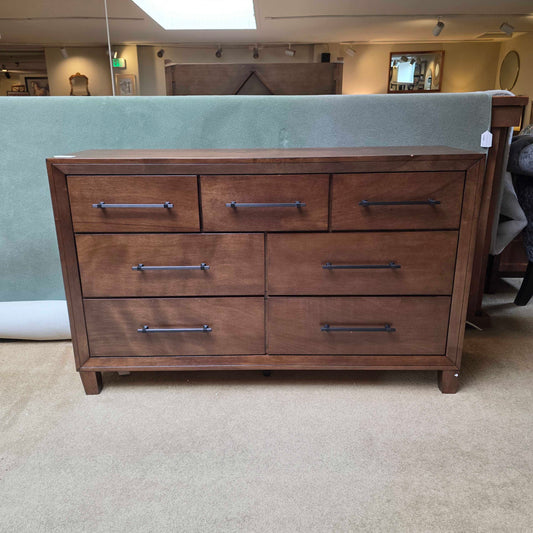 Wooden cabinet with multiple drawers and metal handles in a room setting.