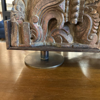 Decorative metal piece with intricate designs on a wooden surface