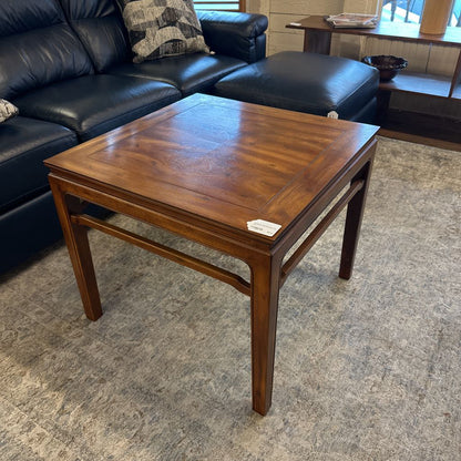 Wooden coffee table in a living room setting with a black leather sofa.