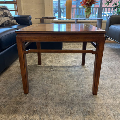 Wooden coffee table in a living room setting with a couch and decorative items.