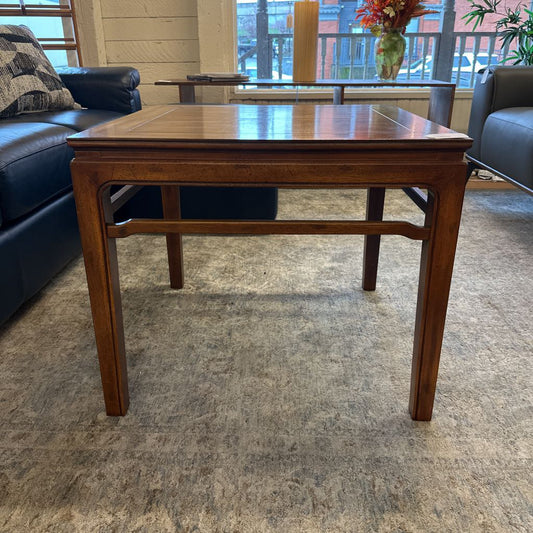 Wooden coffee table in a living room setting with a couch and decorative items.
