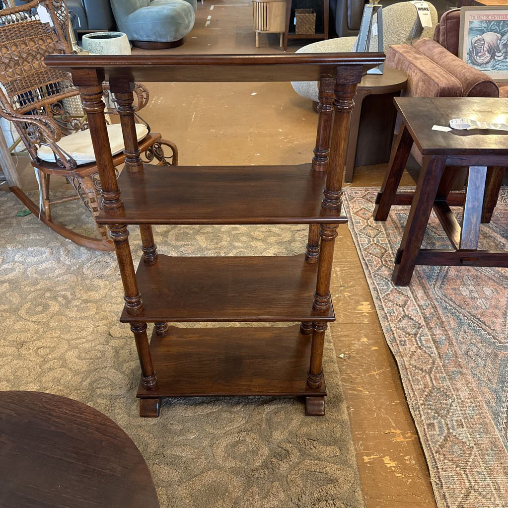 Wooden three-tiered shelf in a room with chairs and a rug.