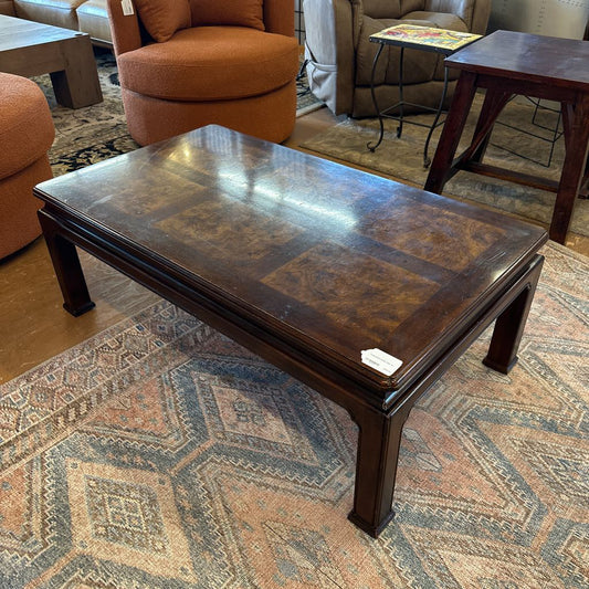 Wooden coffee table with decorative surface in a room with furniture and a rug.