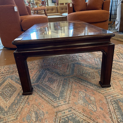 Wooden coffee table on a patterned rug with furniture in the background