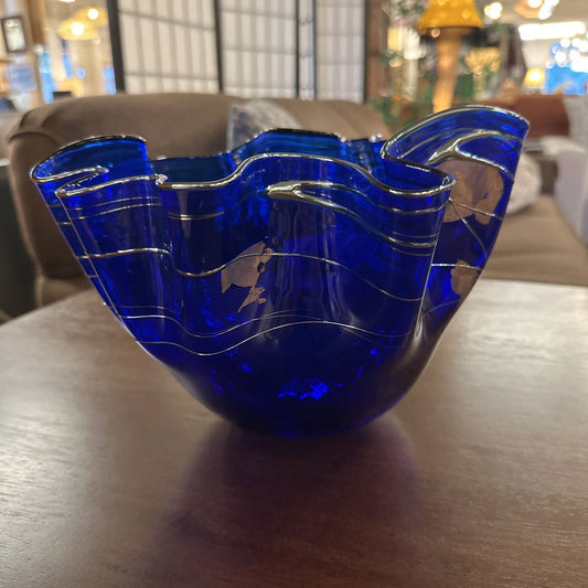 Blue glass bowl with wavy design on a wooden surface
