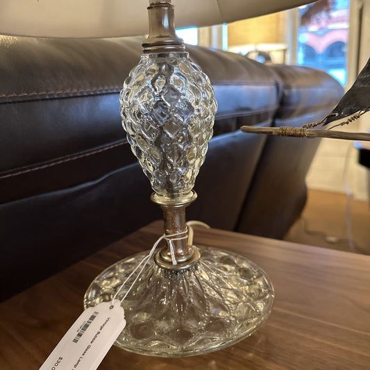 Decorative glass lamp with a tag on a wooden surface, blurred background