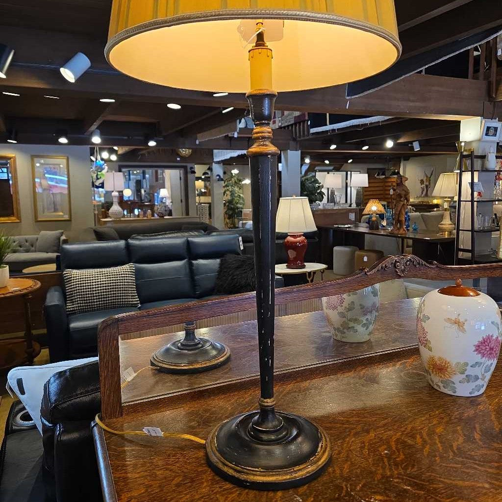 Vintage-style lamp with a yellow shade on a wooden table in a furniture store.