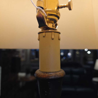 Vintage-style lamp with a beige base and gold fixture against a blurred background