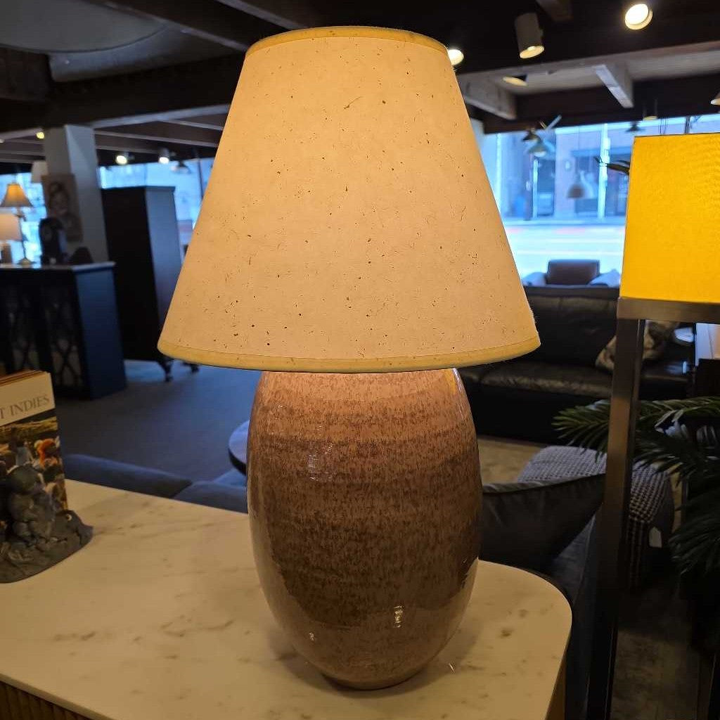 Table lamp with a textured base and yellow shade on a table in an indoor setting.