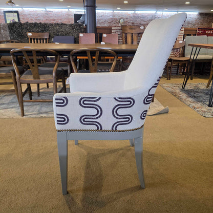 White chair with a patterned cushion on a brown carpet