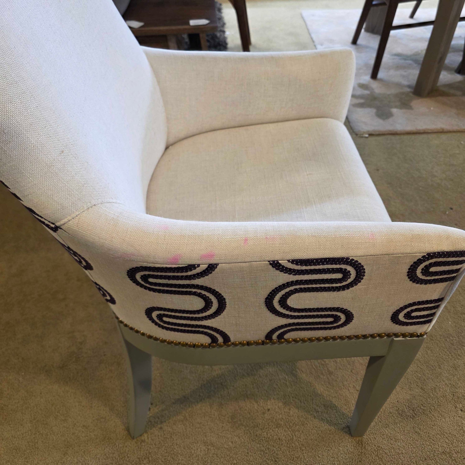 Beige armchair with a decorative pillow featuring black wavy patterns.