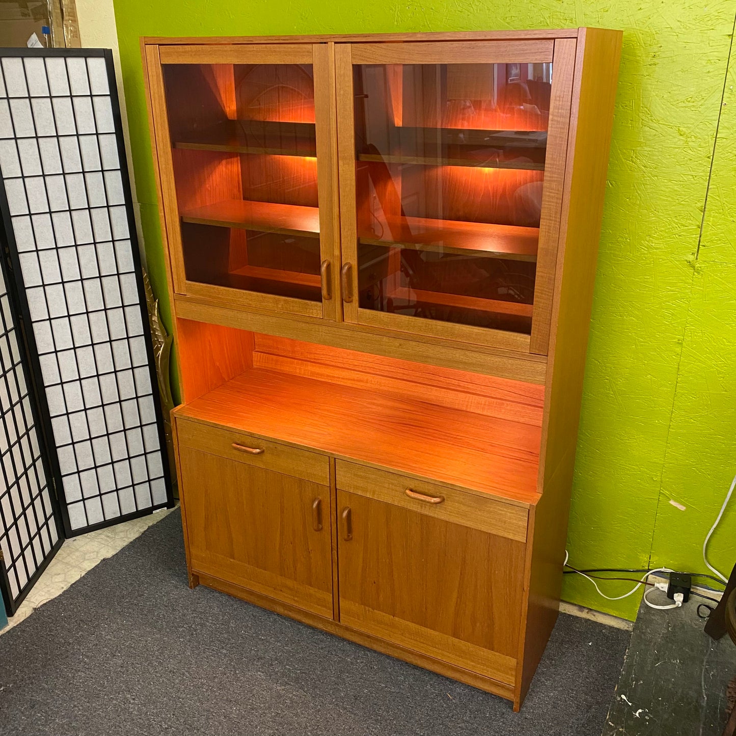 Wooden cabinet with glass doors against a green wall