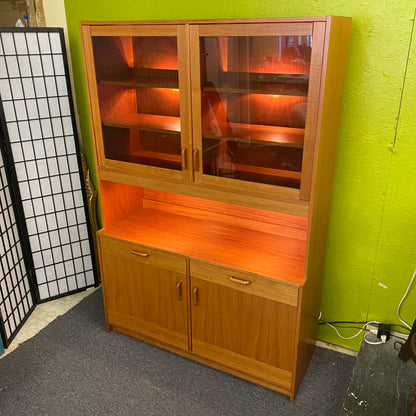 Wooden cabinet with glass doors against a green wall