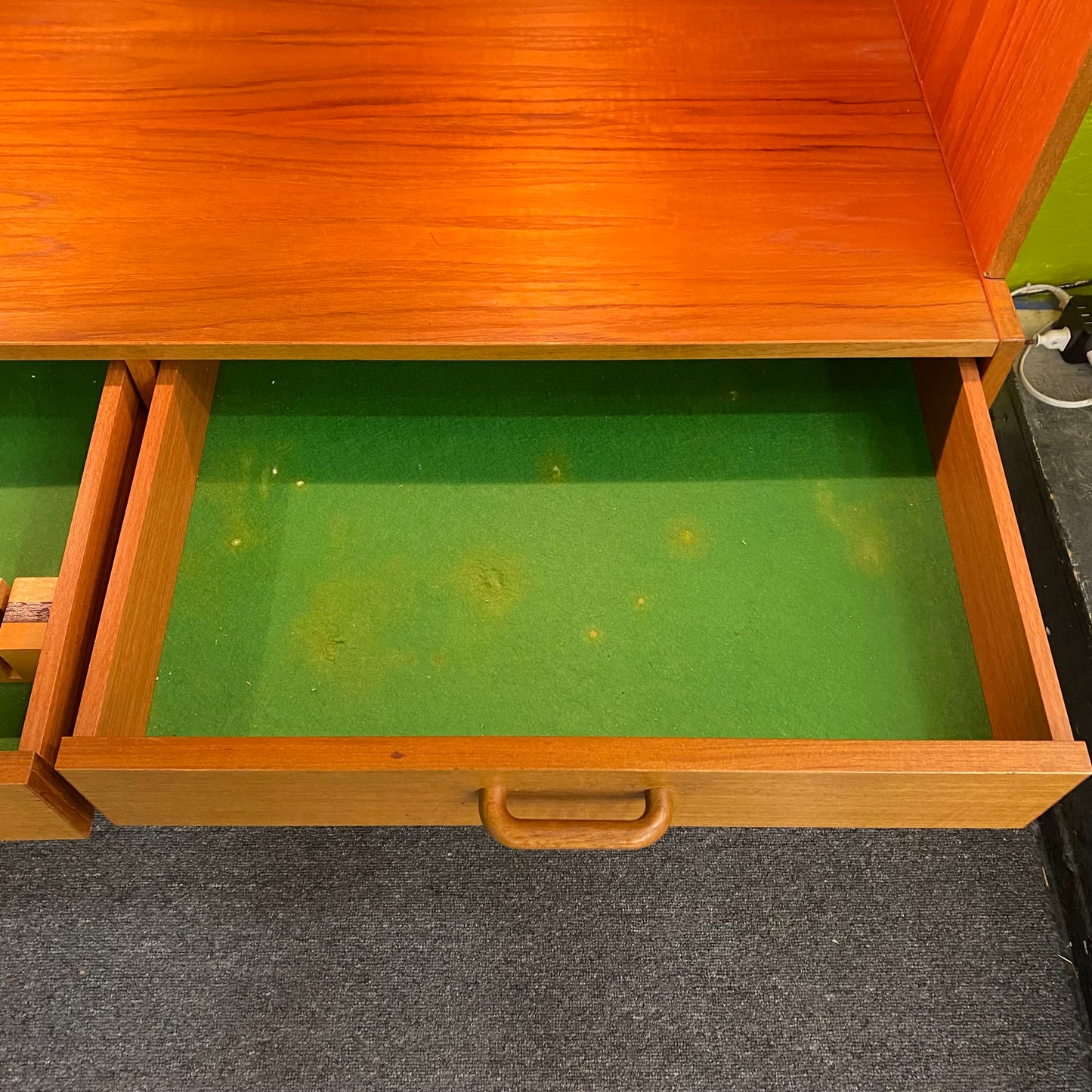 Wooden drawer with green lining on a carpeted floor