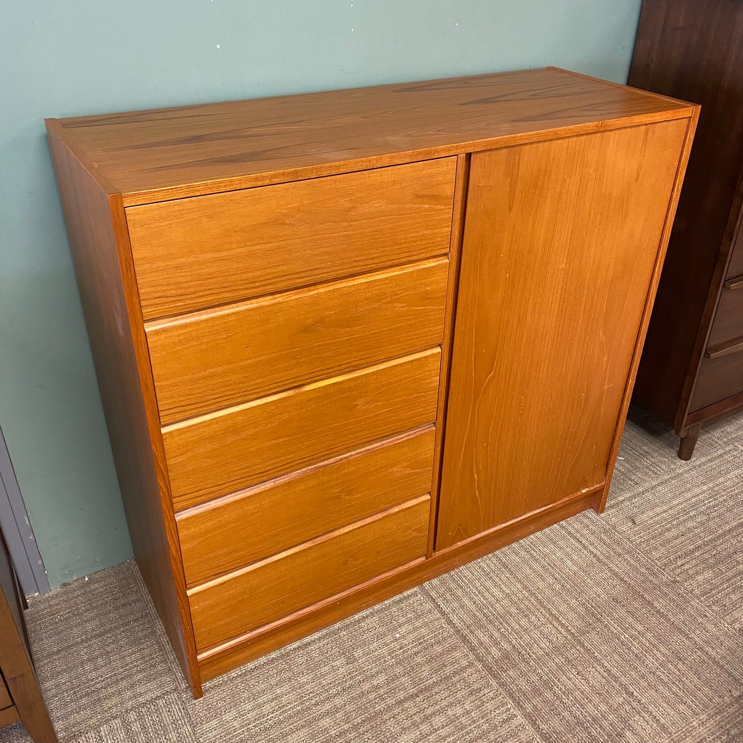 Wooden dresser with multiple drawers against a plain wall.