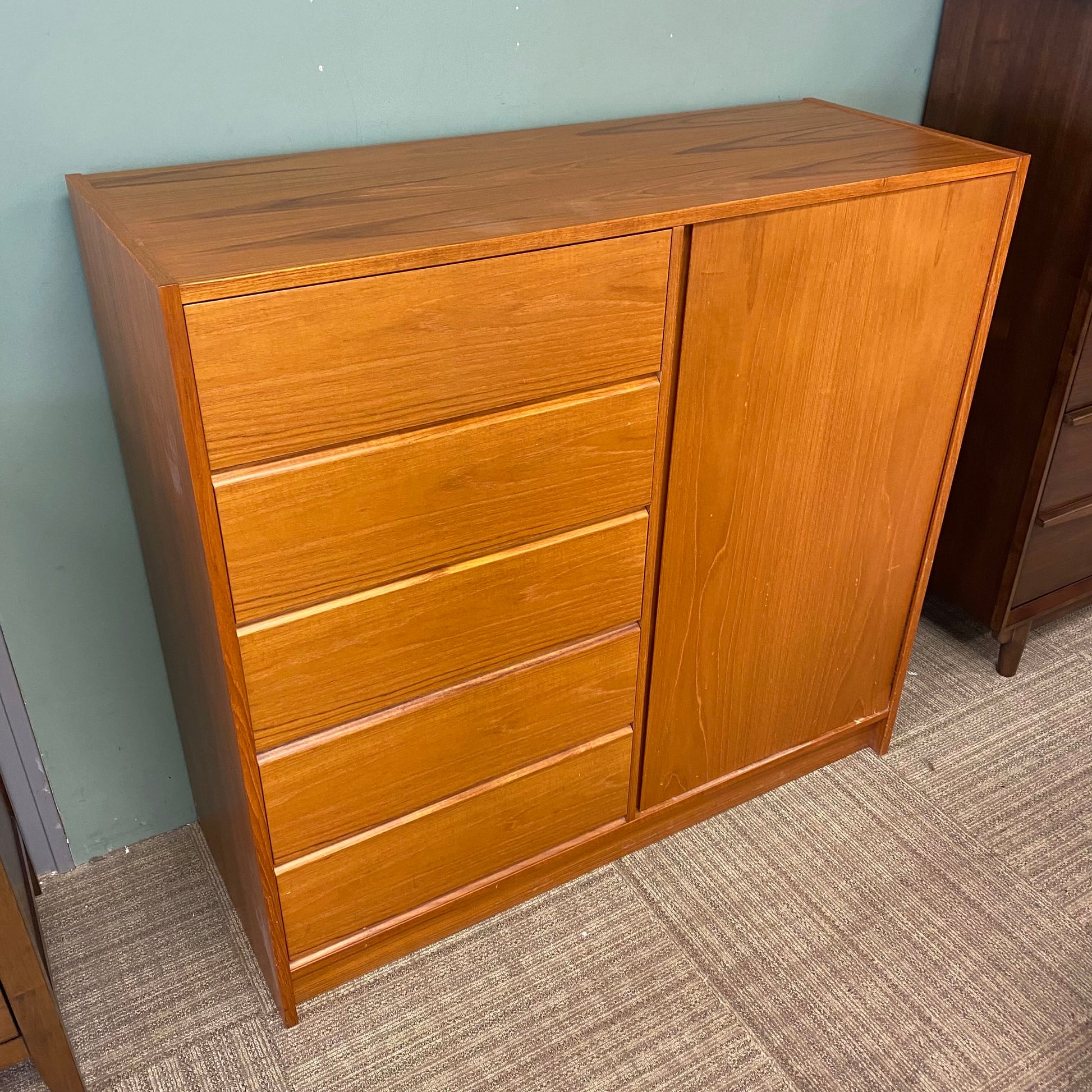 Wooden dresser with multiple drawers against a plain wall.